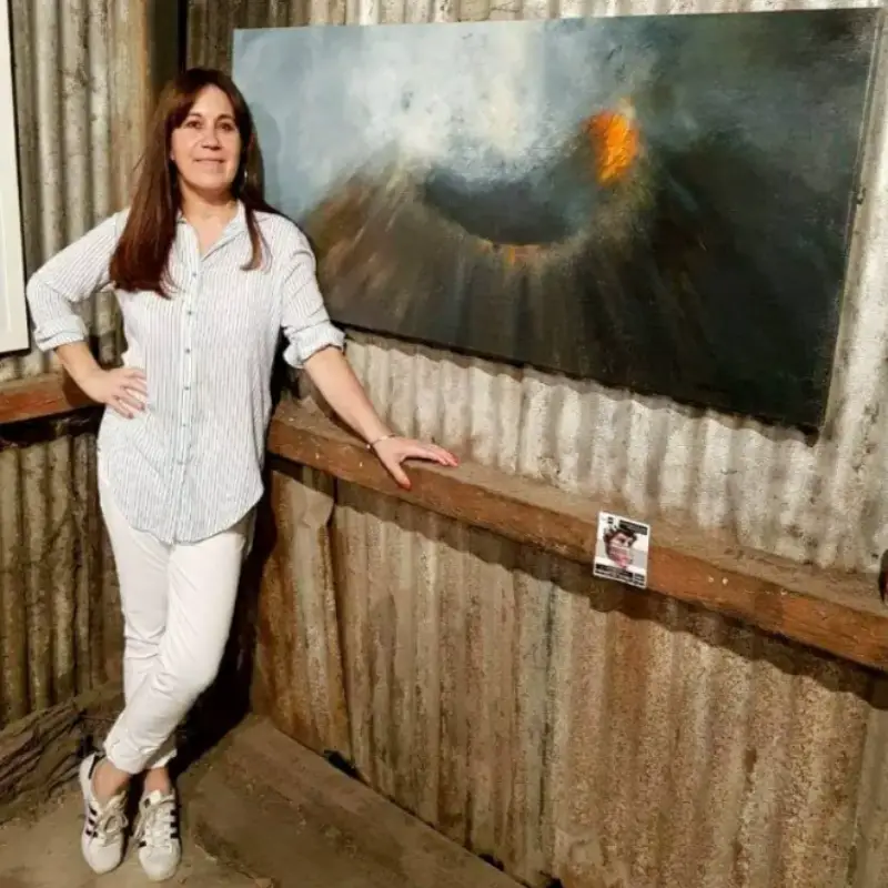 La pintora Nancy Amargan junto a uno de sus cuadros de la serie mi fascinación por los volcanes.