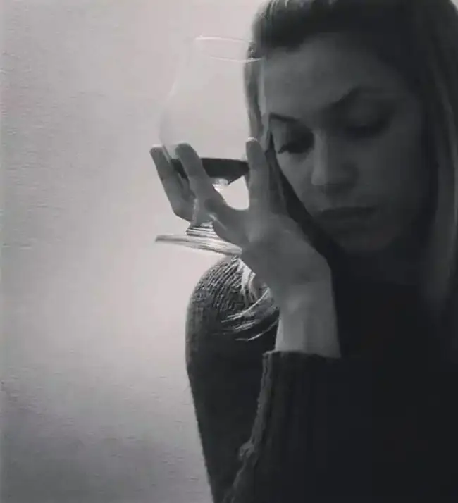 Mujer pensativa, con copa de vino.