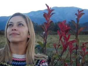 Inés López Barros, en un paisaje con plantas y atrás, cerros.