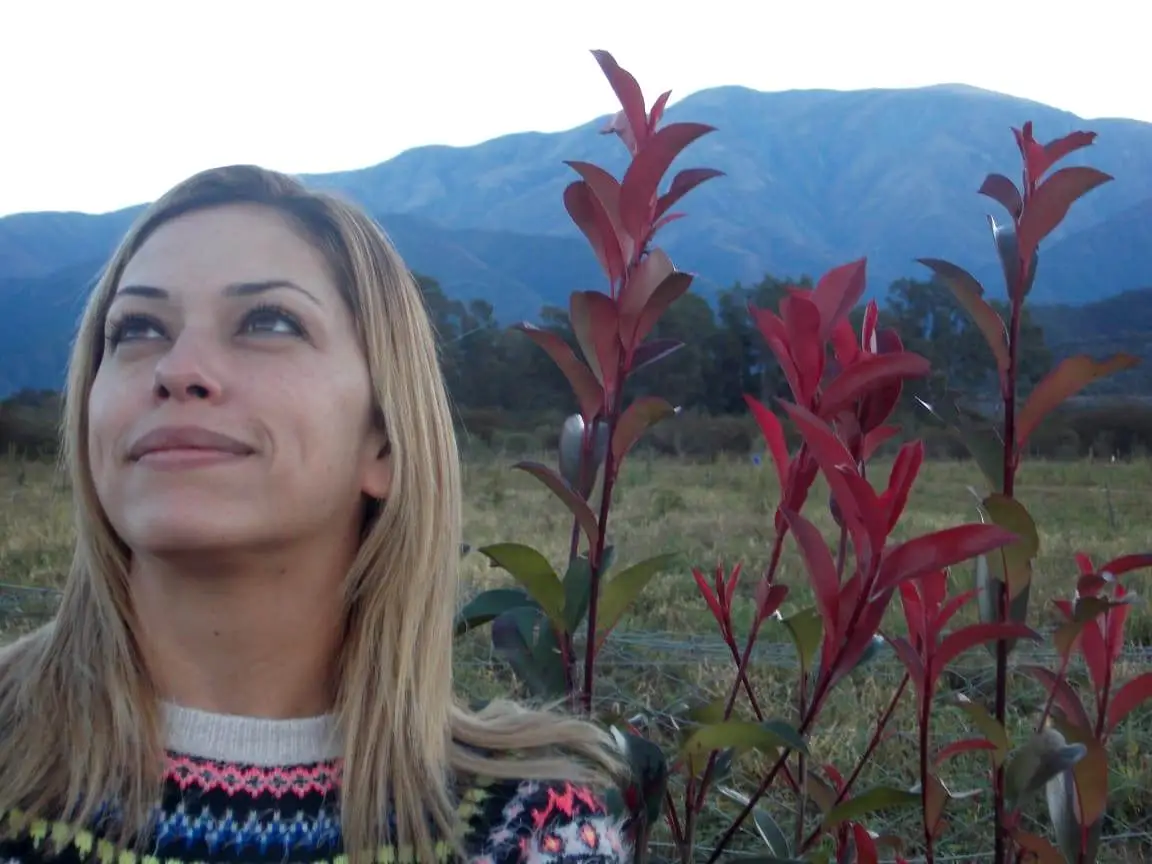 Inés López Barros, en un paisaje con plantas y atrás, cerros.
