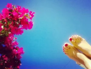 Planta de Santa Rita con fondo de cielo azul, y pies desnudos con uñas pintadas de rojo.