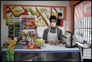 Persona con delantal y barbijo, en el mostrador de una sandwichería salteña.