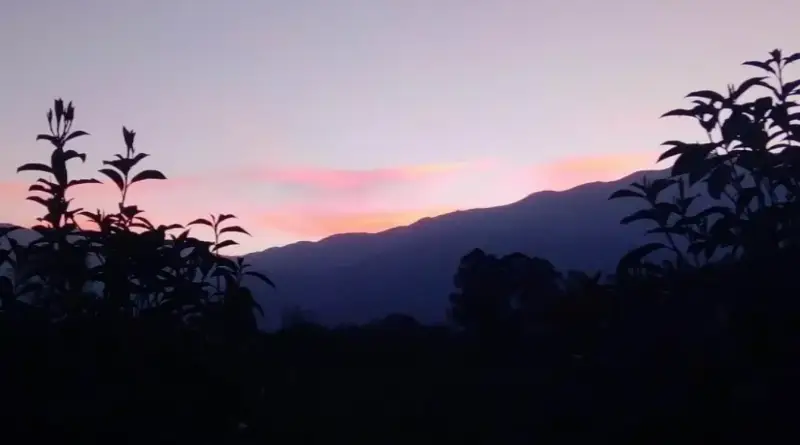 Atardecer en la montaña, con nube teñida de rosa.