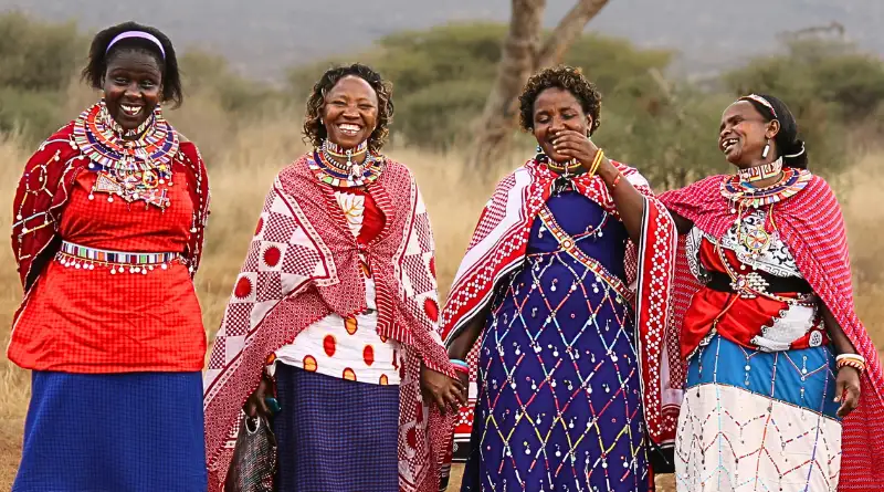 Cuatro mujeres maasai, alegres y sonrientes, con sus coloridos vestidos.